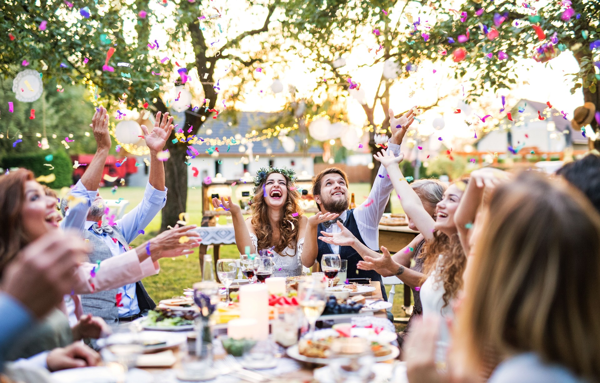 Novia y novio con invitados en la recepción de la boda fuera en el patio trasero.